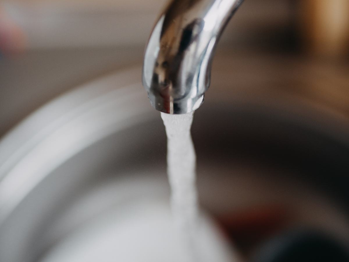 Water running from a kitchen faucet into a stainless steel sink