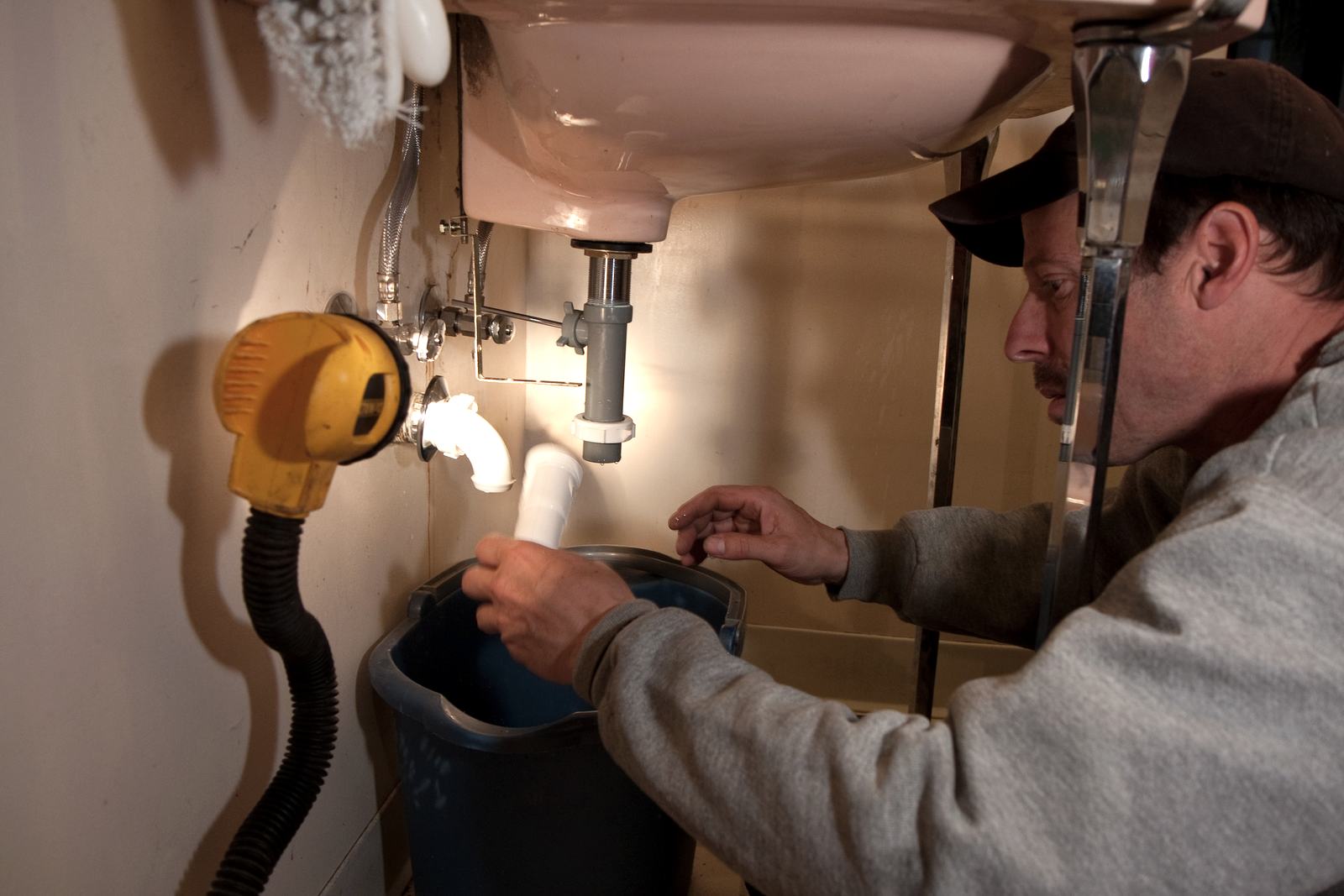 Plumber working under a bathroom sink with a work light