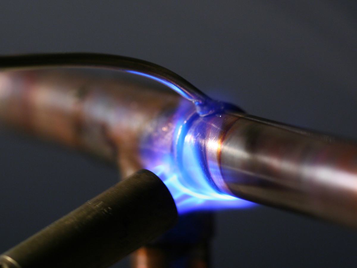 Torch flame heating a copper pipe joint during soldering
