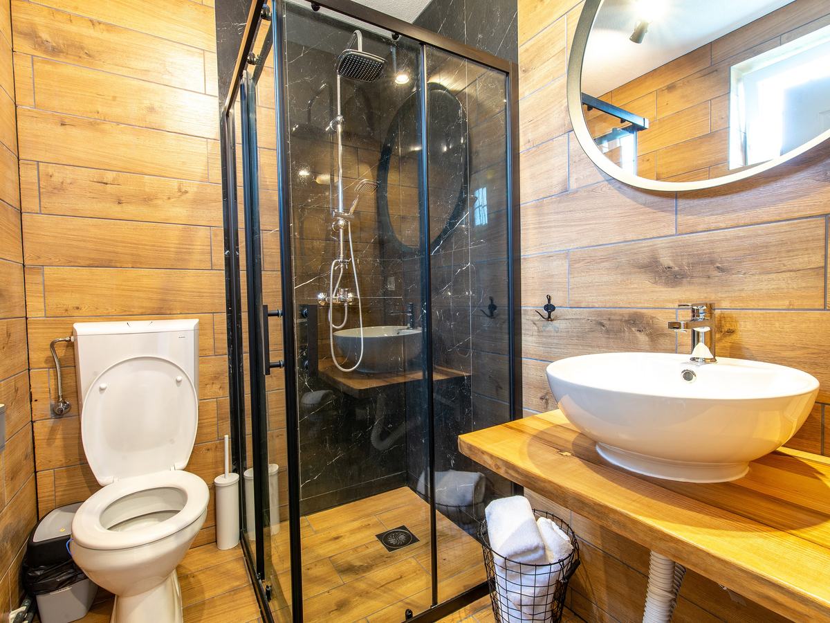 Clean modern bathroom with a white toilet, glass shower, and vessel sink